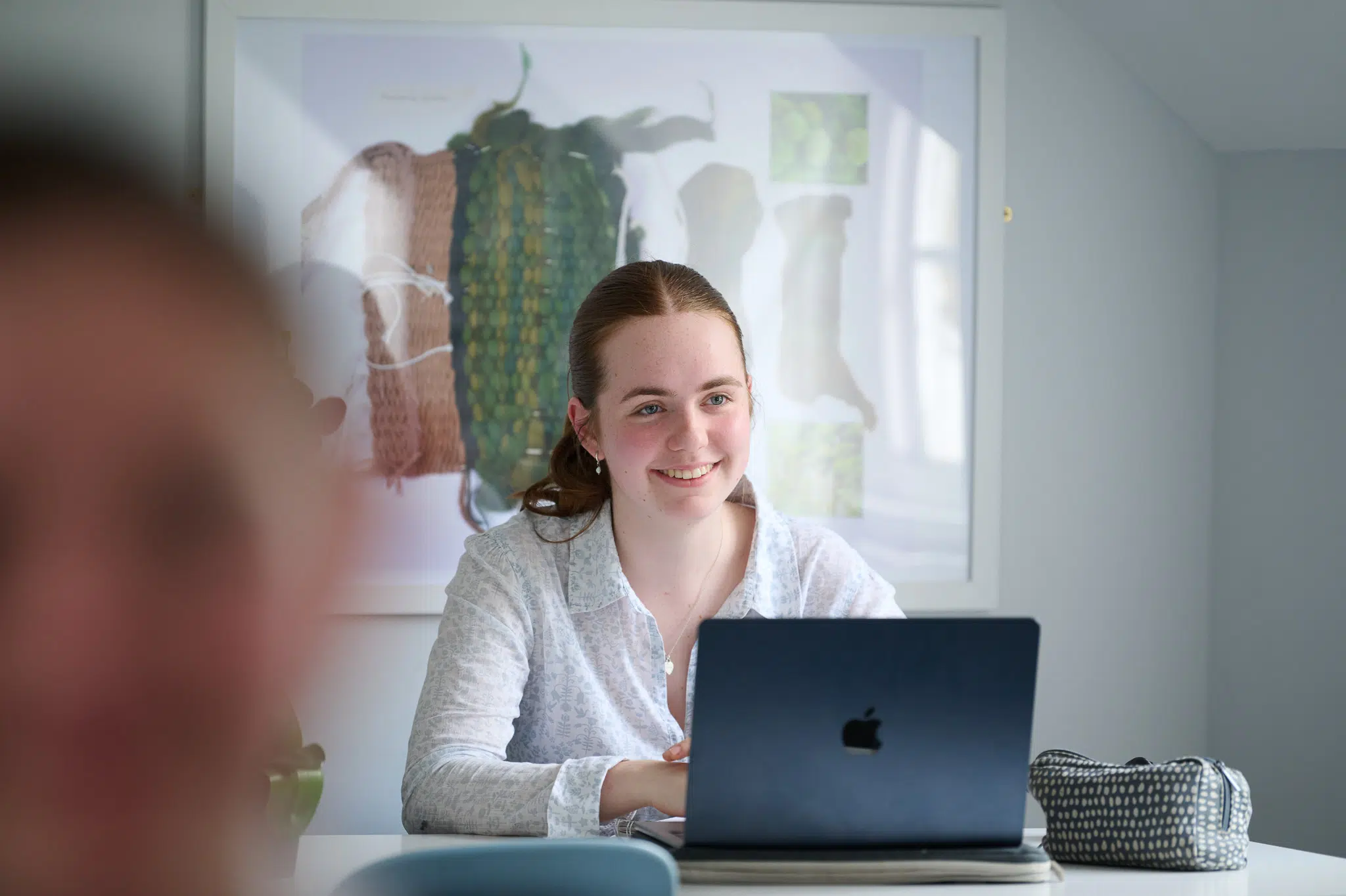 What are the benefits of an all-girls education? A smiling RMS Sixth Form student enjoys studying with her friends, working on her laptop in a bright study room.