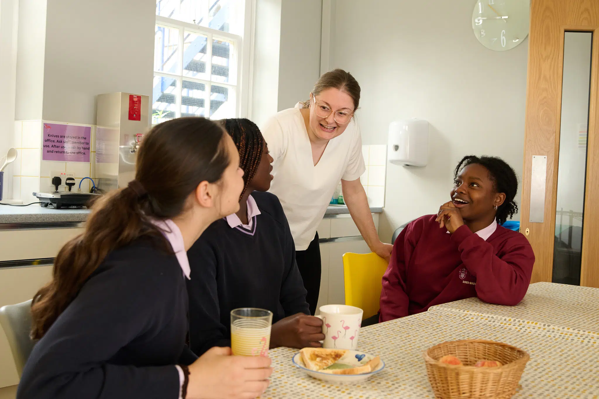 What is pastoral care in schools? An RMS Staff member smiles with boarding students as they eat breakfast
